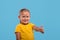 A little smiling girl   giving you an approving gesture against blue background with copy space