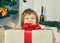 Little smiling girl hiding behind a big gift box. Cheerful cute little child girl with present.