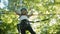 A little smiling girl walking on a rope bridge between the trees