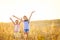 Little smiling girls stand with joyfully raised hands