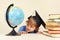 Little smiling professor in academic hat looks at geographical globe