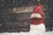 Little snowmans on soft snow on wooden background