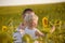 Little son holds a flower sunflower sitting on hands of the father in the background of green field of sunflowers