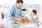 Little son watching his dad cutting vegetables into slices