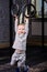 Little sporty boy in the grey sportwear hanging on gymnastic rings at gym.