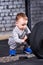 Little sporty boy in the grey sportwear looking and touching at thebarbell against brick wall in the gym.