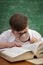 Little student boy reading book with magnifier