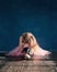 Little student girl of ballet school is crying sitting on floor because of been tired and failure of training