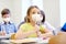 Little student girl in mask on lesson at school