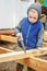 Little studious boy sawing a wooden board. Home construction. Li