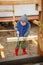 Little studious boy sawing a wooden board. Home construction. Li