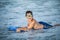 Little surfer learn to ride on surfboard on sea wave. Kid play in summer ocean, learning surfing, riding a wave. Little boy swim