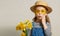 Little surprised child girl in straw hat with a bouquet of yellow flowers in a rubber boot. Mommys little helper