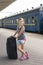 little sweet girl with a big suitcase on a deserted railway platform. girl pulling a large suitcase on the platform. vertical