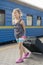 little sweet girl with a big suitcase on a deserted railway platform. girl pulling a large suitcase on the platform. vertical