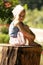 A little sweet girl is sitting on a stump