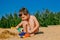 Little tanned boy playing on a sandy beach