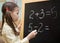 Little teacher. Beautiful young girl is teaching at home on blackboard.