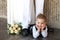 The little thoughtful boy lies on a floor with a bridal bouquet at a wedding