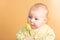Little three-month girl with a yellow tulip on a beige background in the studio, concept of tenderness and love with a newborn
