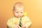 Little three-month girl with a yellow tulip on a beige background in the studio, concept of tenderness and love with a newborn