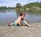 A little three-year-old dark tanned boy plays with pebbles on the lake in the summer