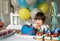 Little three years old boy making wish looking at candles on his birthday cake at home