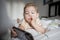 Little toddle girl playing with smartphone laying on the bed at home. Caucasian toddler girl.