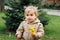 Little toddler baby girl in trench coat picking yellow dandelions in spring garden. Cute baby girl enjoying the simple