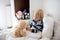 Little toddler blond child, playing with teddy bear in bed, while being sick, checking his temperature