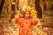 Little toddler boy in crown of yellow leaves standing in colorful autumn park and showing two thumbs up.