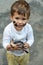 Little toddler boy with dirty face and dirty clothes looking through a magnifying glass on nature.