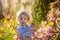 Little toddler boy, eating chocolate bunny in garden on sunset, easter eggs