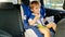 Little toddler boy feeling hungry and eating while travelling by car in child safety seat