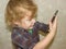 A little toddler boy holds a gadget in his hands and clicks on the smartphone screen.