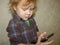 A little toddler boy holds a gadget in his hands and clicks on the smartphone screen.