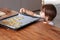 Little toddler boy making homemade cookies putting shapes at baking tray at home.