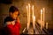 Little toddler boy, praying in chapel with candles in front