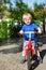 Little toddler boy riding on his bycicle in summer