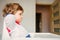 Little toddler boy sitting in a chair for feeding in a room in breakfast time