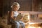 Little toddler boy, sitting on old vintage bench, holding books in attic