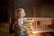 Little toddler boy, sitting on old vintage bench, holding books in attic