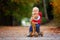 Little toddler boy with teddy bear, riding wooden dog balance bi