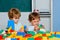 Little toddler boys playing with toy constructors. Toy mess in child room. Educational games for kids.