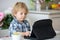 Little toddler child, blond boy, licking lollipop while watching movie on tablet