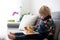 Little toddler child, blond boy, reading book with sweet chicks