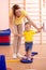 Little toddler doing steps on fitness plate with mom`s help in the gym