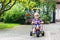 Little toddler driving tricycle or bicycle in home garden