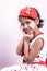 Little toddler girl child in white and red patch gown wearing colorful necklace holding hands on cheek