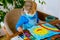 Little toddler girl in medical mask painting rainbow with water colors during pandemic coronavirus quarantine disease